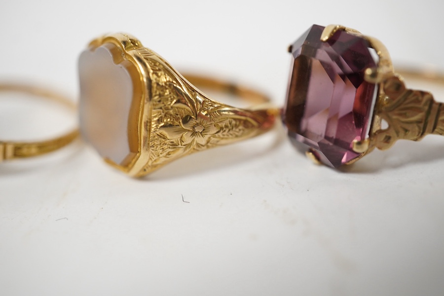 A group of four rings, comprising: a chalcedony signet ring with engraved floral shoulders, size L, partial British hallmarks for 15ct gold; a synthetic ruby and diamond five-stone ring, size N, stamped 18CT; a ring set